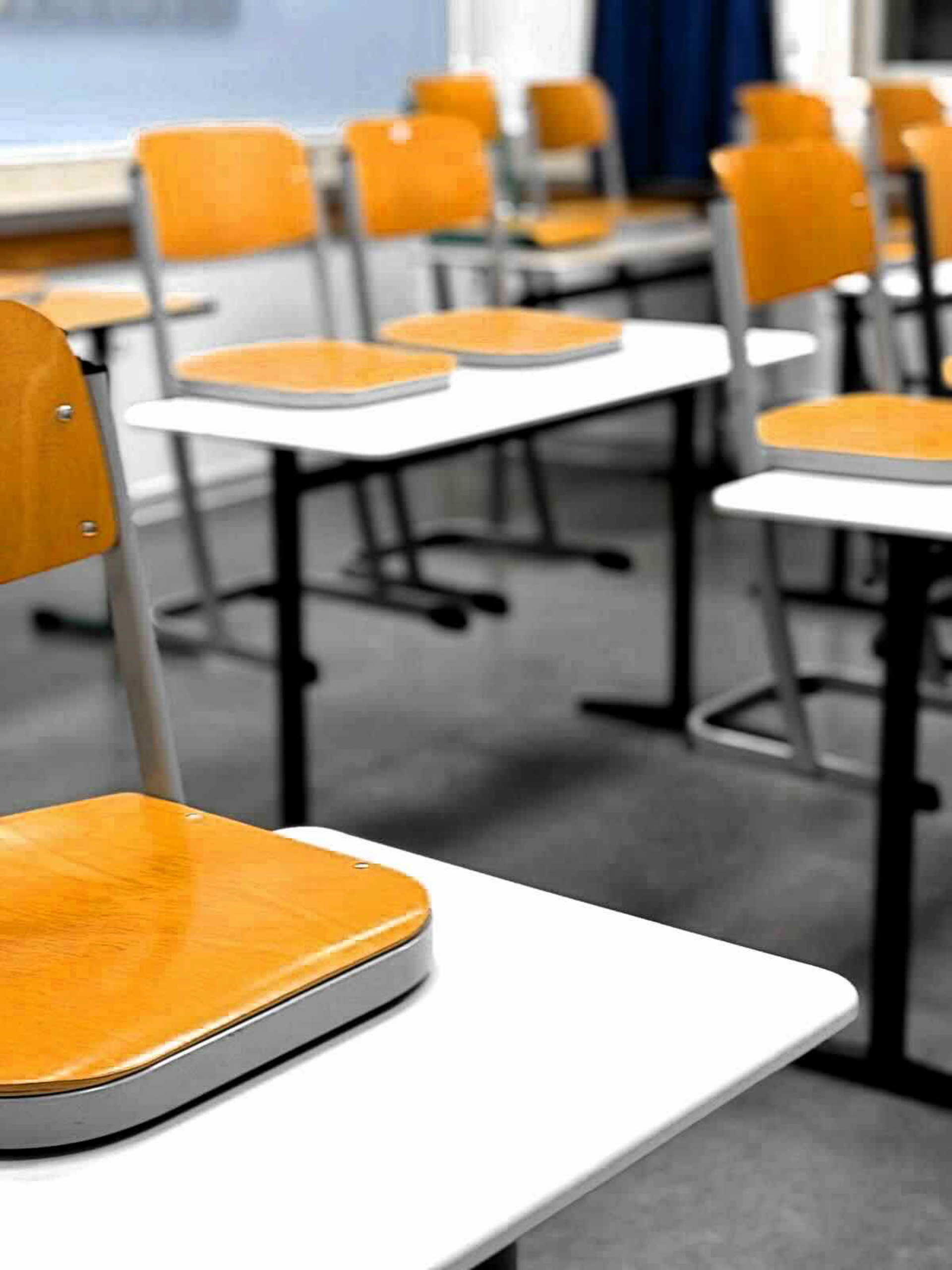 Professionelle Schulreinigung in Berlin Klassenraum mit Schultischen und orangefarbenen Stühlen